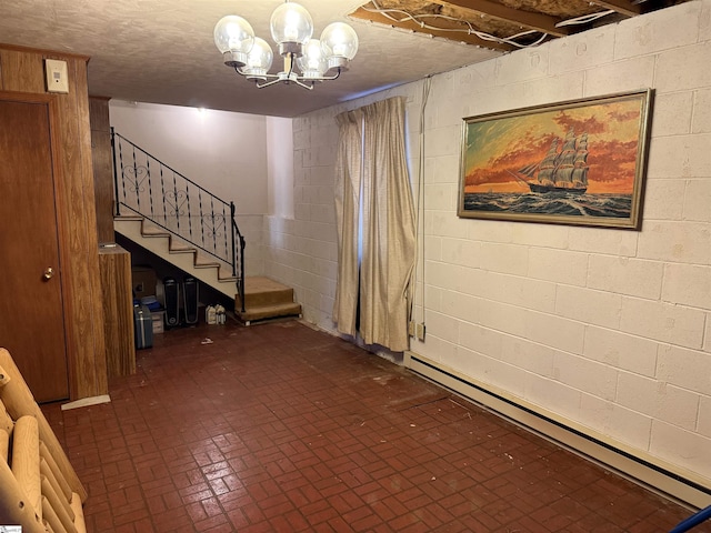 basement featuring an inviting chandelier, a textured ceiling, and a baseboard heating unit