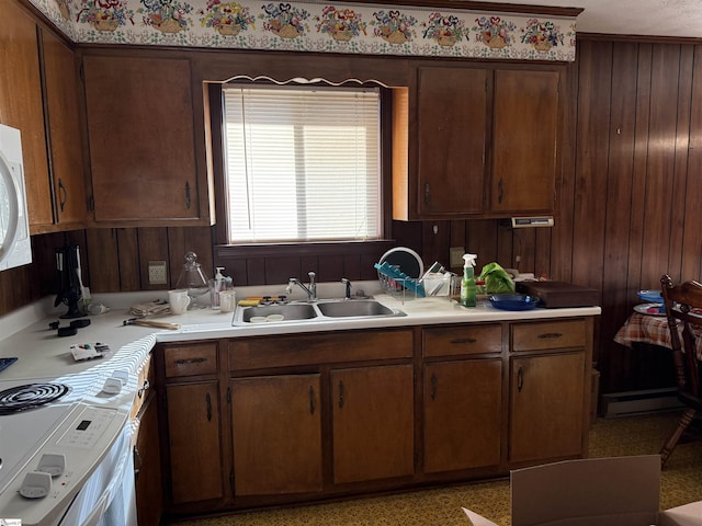 kitchen with wood walls, dark brown cabinetry, sink, and range