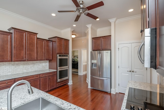 kitchen featuring dark wood-type flooring, sink, light stone countertops, ornamental molding, and stainless steel appliances