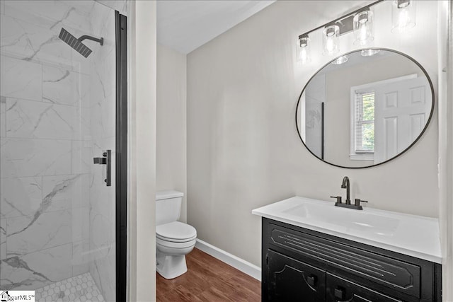 bathroom featuring hardwood / wood-style floors, vanity, toilet, and a tile shower