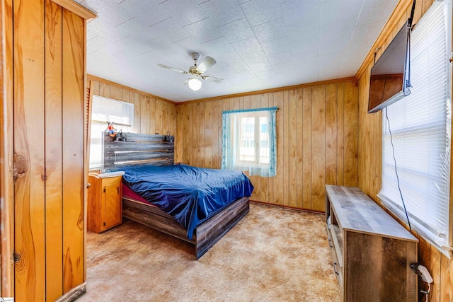 bedroom with ceiling fan, crown molding, light carpet, and wooden walls