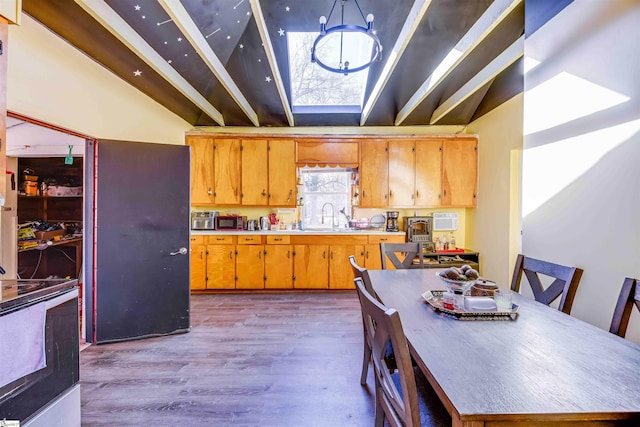 kitchen with hanging light fixtures, sink, light hardwood / wood-style floors, and stove