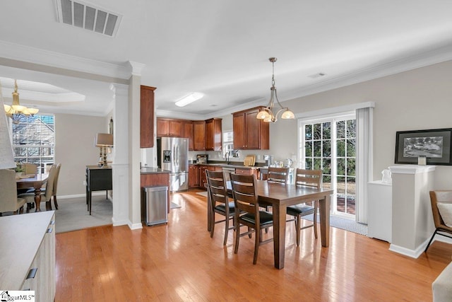 dining room with a chandelier, light wood-type flooring, and ornamental molding