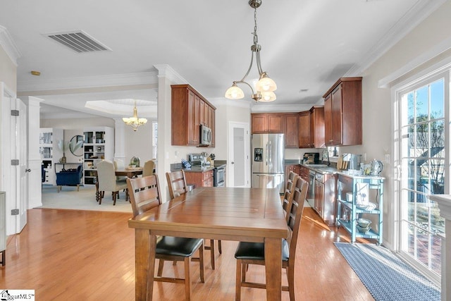 dining area with light hardwood / wood-style floors, a chandelier, and ornamental molding