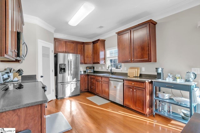 kitchen featuring appliances with stainless steel finishes, light hardwood / wood-style floors, ornamental molding, and sink