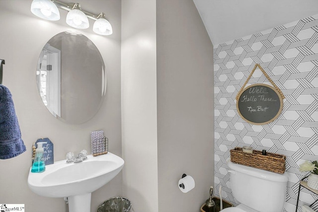 bathroom with toilet, sink, and vaulted ceiling