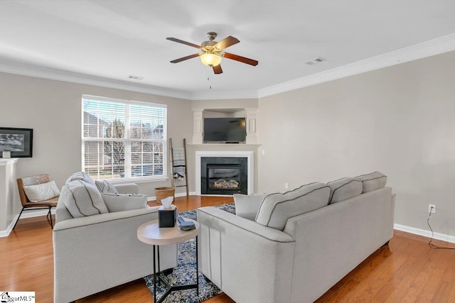 living room featuring light hardwood / wood-style floors, ceiling fan, and crown molding