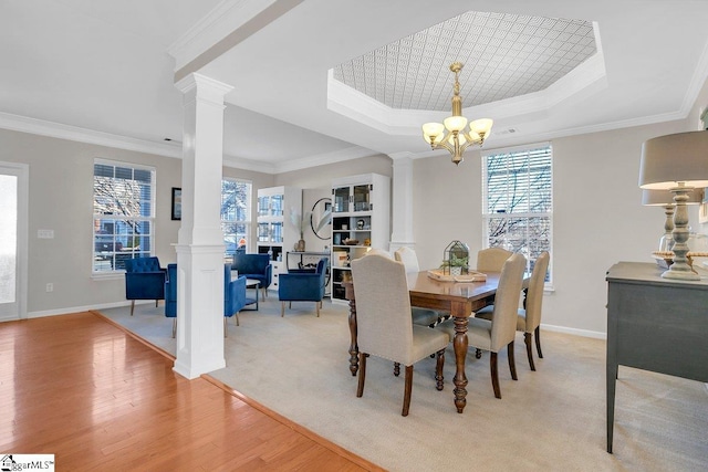 dining room with ornate columns, ornamental molding, a tray ceiling, light hardwood / wood-style flooring, and a chandelier