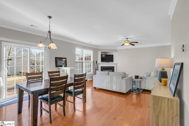 dining area featuring ornamental molding, ceiling fan with notable chandelier, hardwood / wood-style flooring, and a healthy amount of sunlight