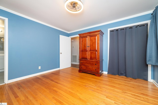 unfurnished bedroom featuring ensuite bathroom, light hardwood / wood-style floors, and crown molding