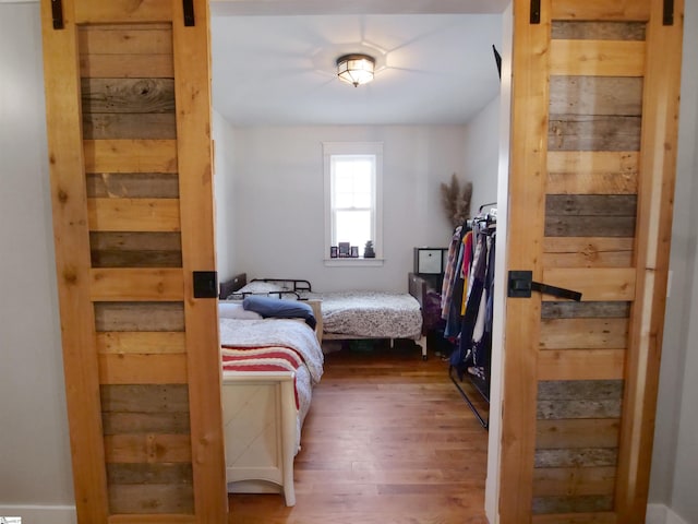 bedroom with a barn door and hardwood / wood-style flooring