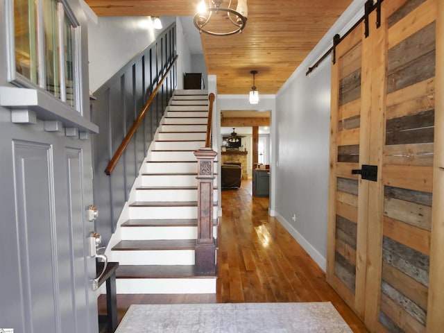 stairs featuring hardwood / wood-style floors, a barn door, crown molding, and wood ceiling