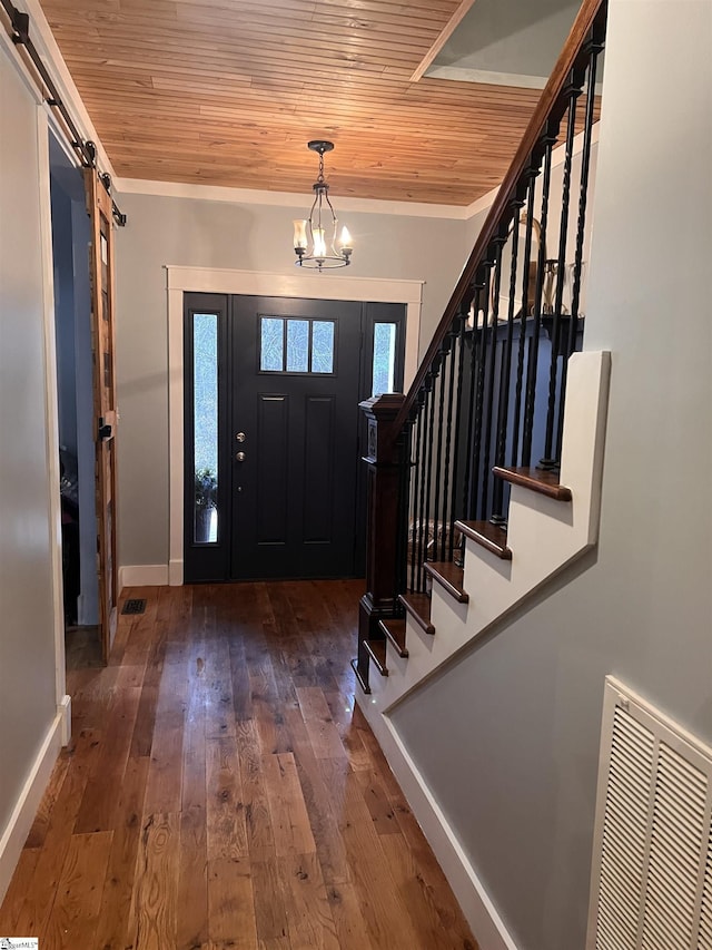 entrance foyer with hardwood / wood-style flooring, a notable chandelier, a barn door, and wooden ceiling