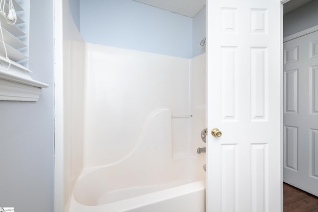 bathroom with hardwood / wood-style floors, shower / bathtub combination, and a textured ceiling