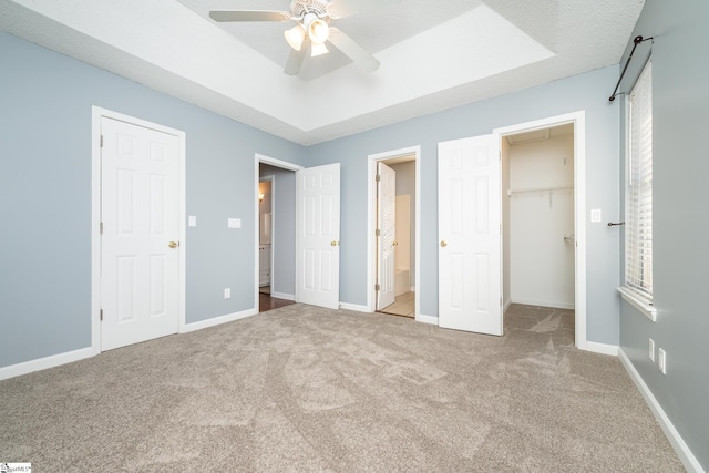 unfurnished bedroom with carpet flooring, a textured ceiling, ceiling fan, a spacious closet, and connected bathroom