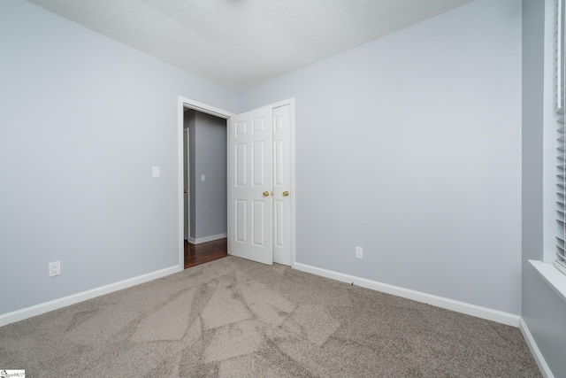 unfurnished room with carpet and a textured ceiling