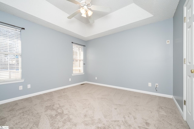 carpeted empty room with a textured ceiling, a raised ceiling, and ceiling fan