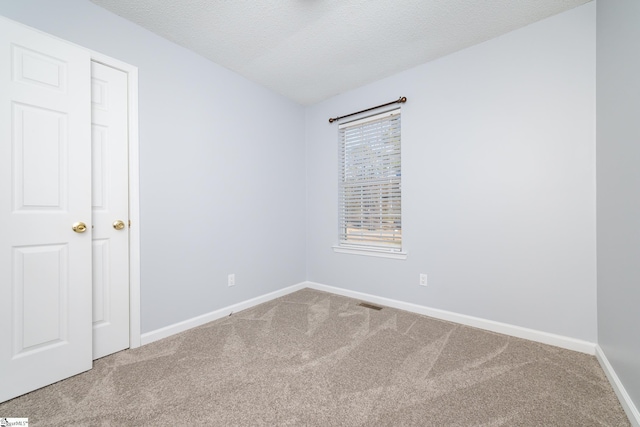 carpeted empty room with a textured ceiling