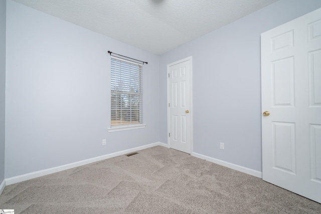 spare room with light colored carpet and a textured ceiling