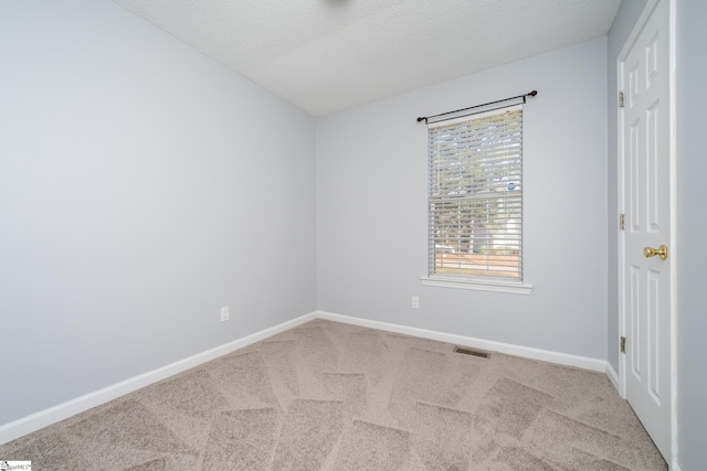 empty room with light colored carpet and a textured ceiling