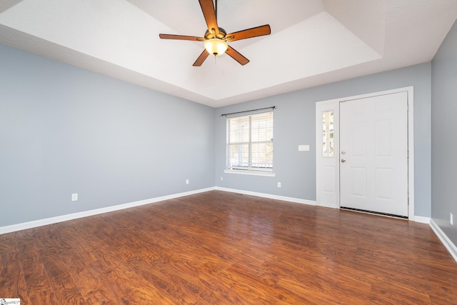 entryway with a raised ceiling, ceiling fan, and dark wood-type flooring