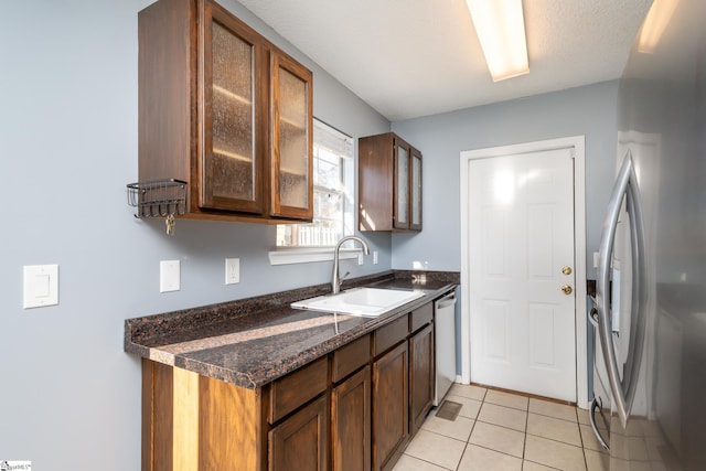 kitchen with light tile patterned floors, sink, appliances with stainless steel finishes, and dark stone counters