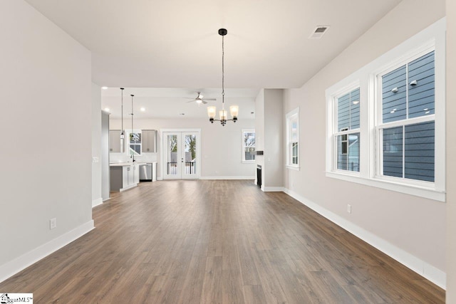 unfurnished living room with ceiling fan with notable chandelier, dark hardwood / wood-style flooring, and french doors