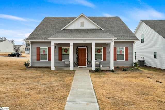 bungalow-style home featuring a porch, a front lawn, and central air condition unit