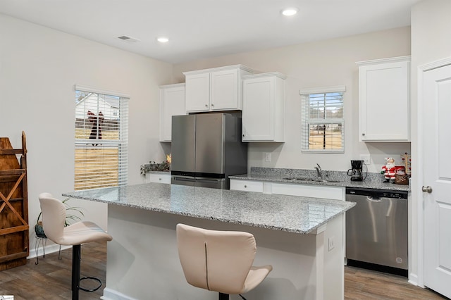 kitchen with a breakfast bar area, white cabinetry, light stone countertops, and appliances with stainless steel finishes