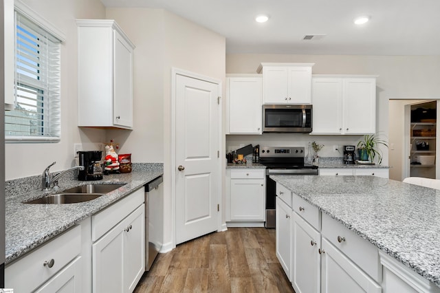 kitchen featuring light stone countertops, sink, white cabinets, and stainless steel appliances