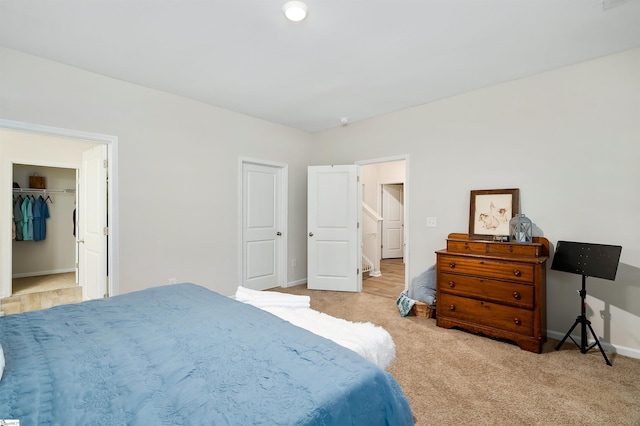 bedroom with a walk in closet, light carpet, and a closet