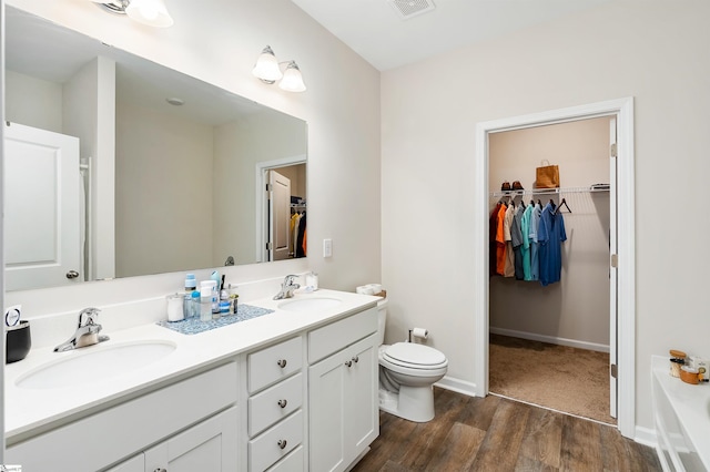 bathroom with a bath, vanity, hardwood / wood-style flooring, and toilet