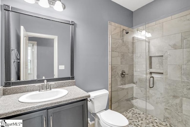 bathroom featuring toilet, vanity, and a shower with shower door