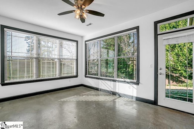 spare room with a healthy amount of sunlight, ceiling fan, and concrete flooring