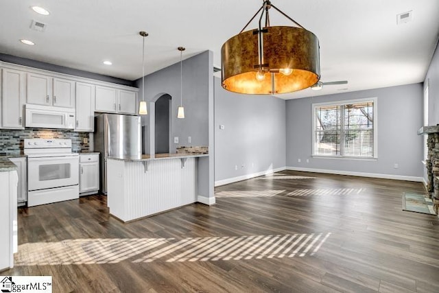 kitchen featuring white cabinetry, white appliances, a kitchen breakfast bar, kitchen peninsula, and hanging light fixtures