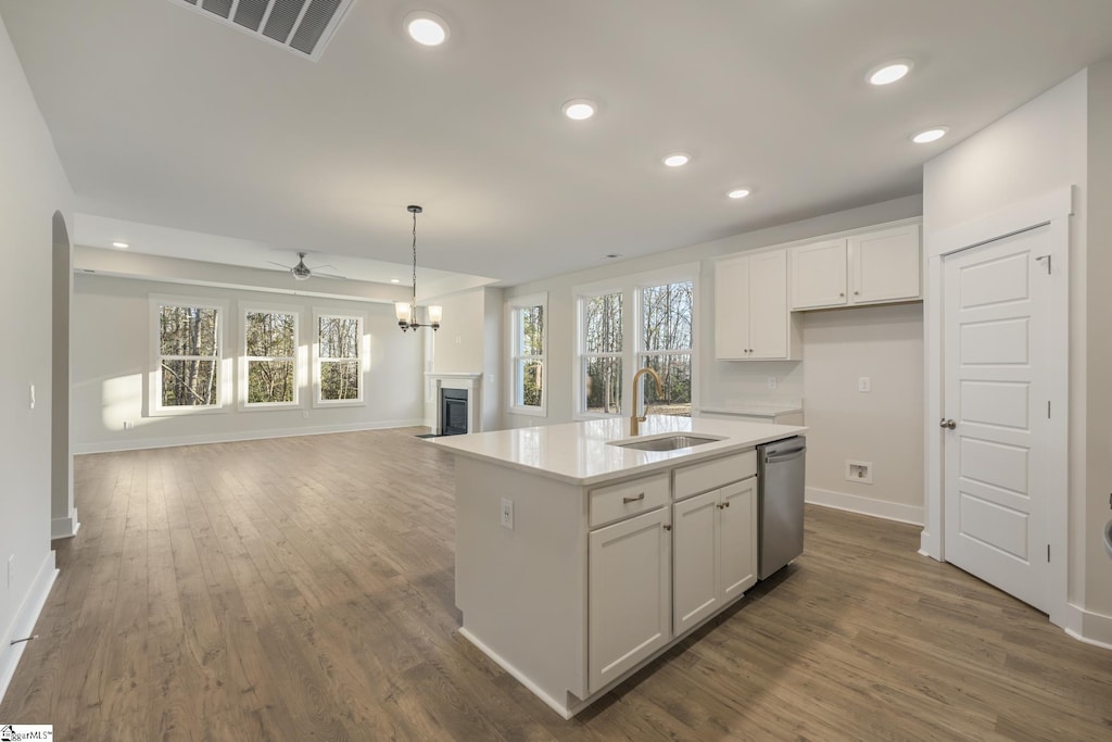 kitchen with ceiling fan, a kitchen island with sink, sink, dishwasher, and white cabinetry