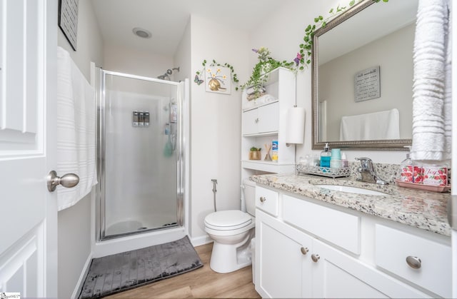 bathroom with toilet, a shower with door, hardwood / wood-style floors, and vanity