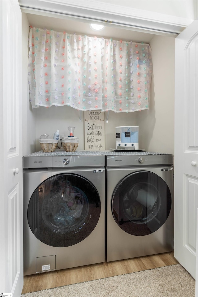 clothes washing area with light hardwood / wood-style flooring and washing machine and clothes dryer