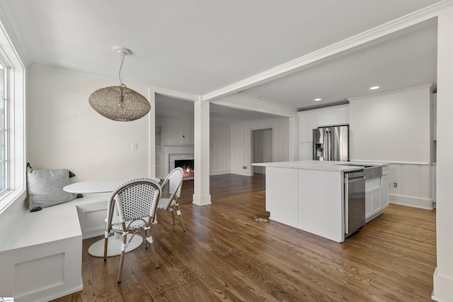 kitchen with stainless steel refrigerator with ice dispenser, white cabinetry, ornamental molding, and dark wood-type flooring