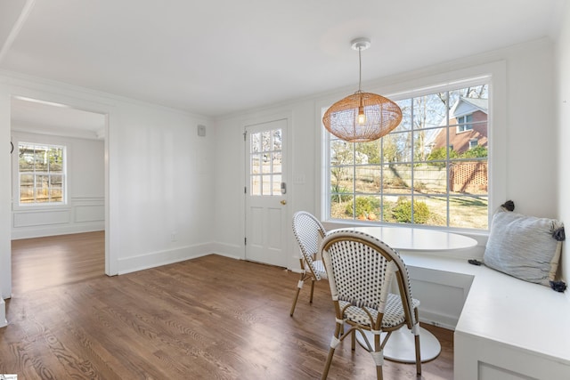 dining space with breakfast area, crown molding, and dark wood-type flooring