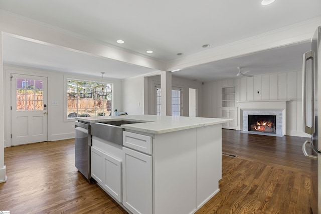 kitchen with a kitchen island with sink, white cabinets, decorative light fixtures, dark hardwood / wood-style flooring, and stainless steel appliances