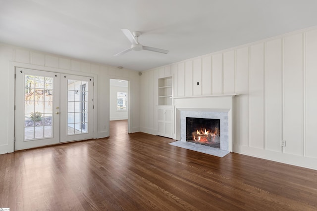 unfurnished living room featuring ceiling fan, built in features, dark wood-type flooring, and french doors