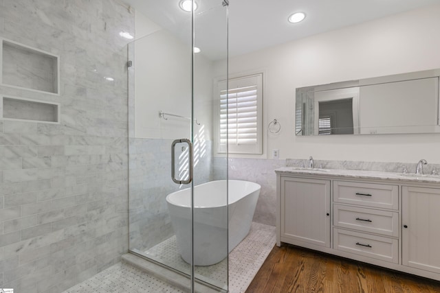 bathroom featuring vanity, plus walk in shower, tile walls, and hardwood / wood-style flooring