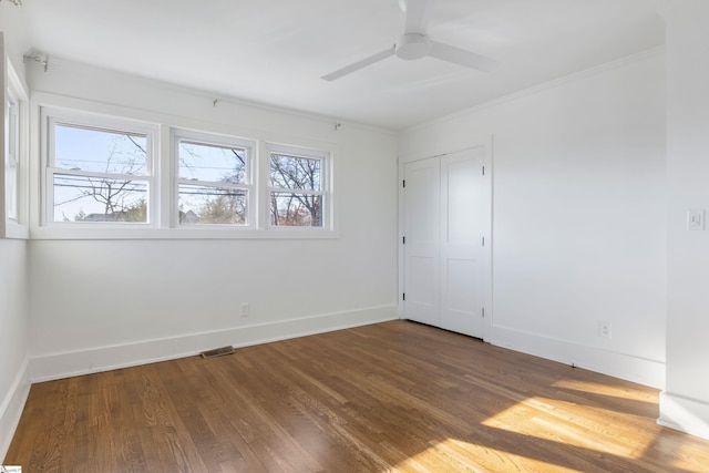 unfurnished bedroom featuring ceiling fan, a closet, crown molding, and dark hardwood / wood-style floors