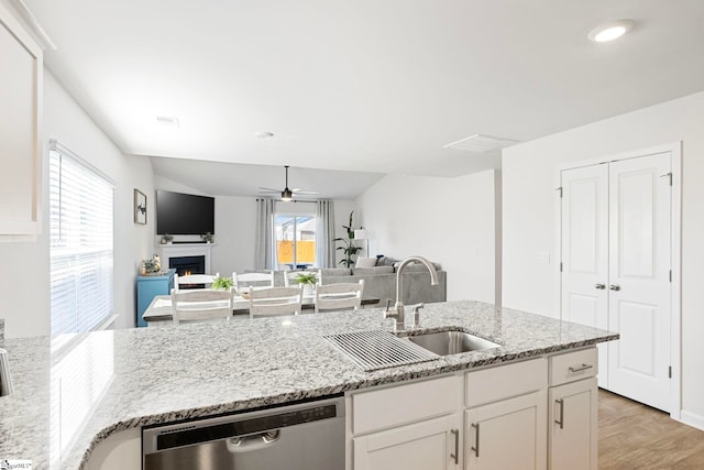 kitchen with white cabinets, sink, stainless steel dishwasher, ceiling fan, and light stone countertops