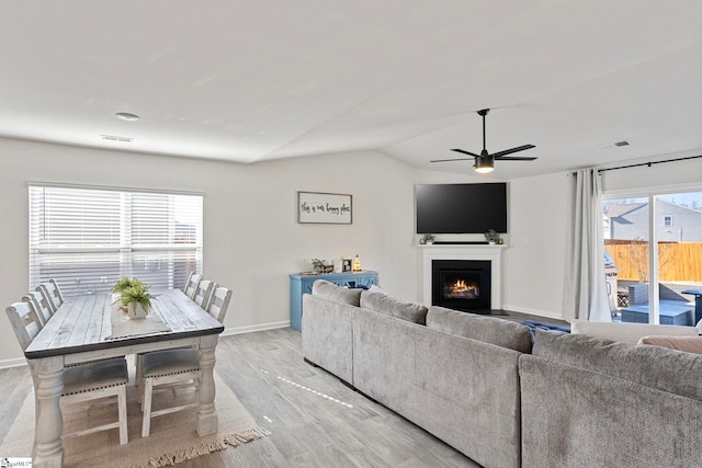 living room featuring ceiling fan, lofted ceiling, and light hardwood / wood-style flooring