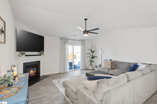 living room featuring ceiling fan, wood-type flooring, and vaulted ceiling