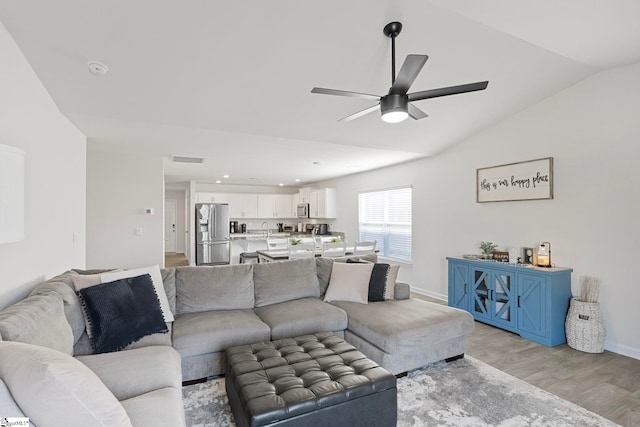 living room with ceiling fan, light hardwood / wood-style floors, and lofted ceiling