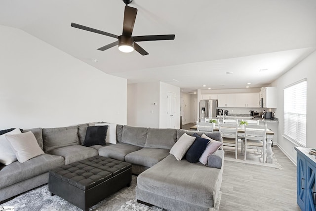 living room featuring ceiling fan, vaulted ceiling, and light hardwood / wood-style flooring