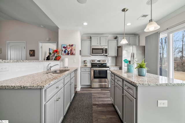 kitchen with sink, stainless steel appliances, tasteful backsplash, kitchen peninsula, and decorative light fixtures